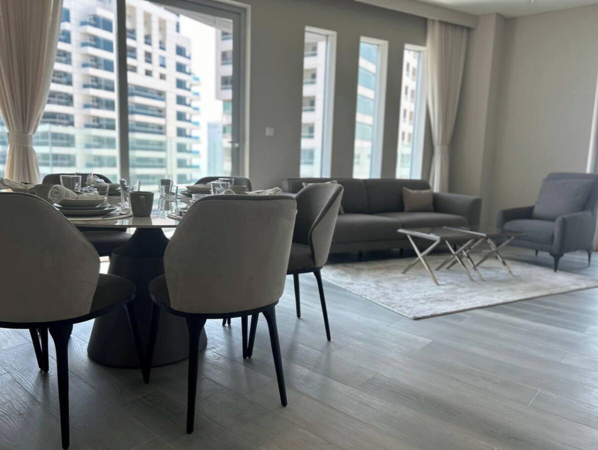 Een moderne eetruimte met een ronde tafel en stoelen, een bank en een salontafel.