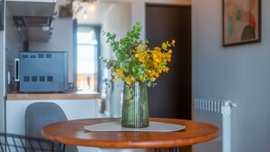 A modern kitchen with a wooden table, a vase with yellow flowers, and a kitchen appliance. - HB apartments Marukhis (Tbilisi)