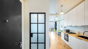 A modern kitchen with white cabinets, a wooden countertop, and a black stove. - HB apartments Marukhis (Tbilisi)