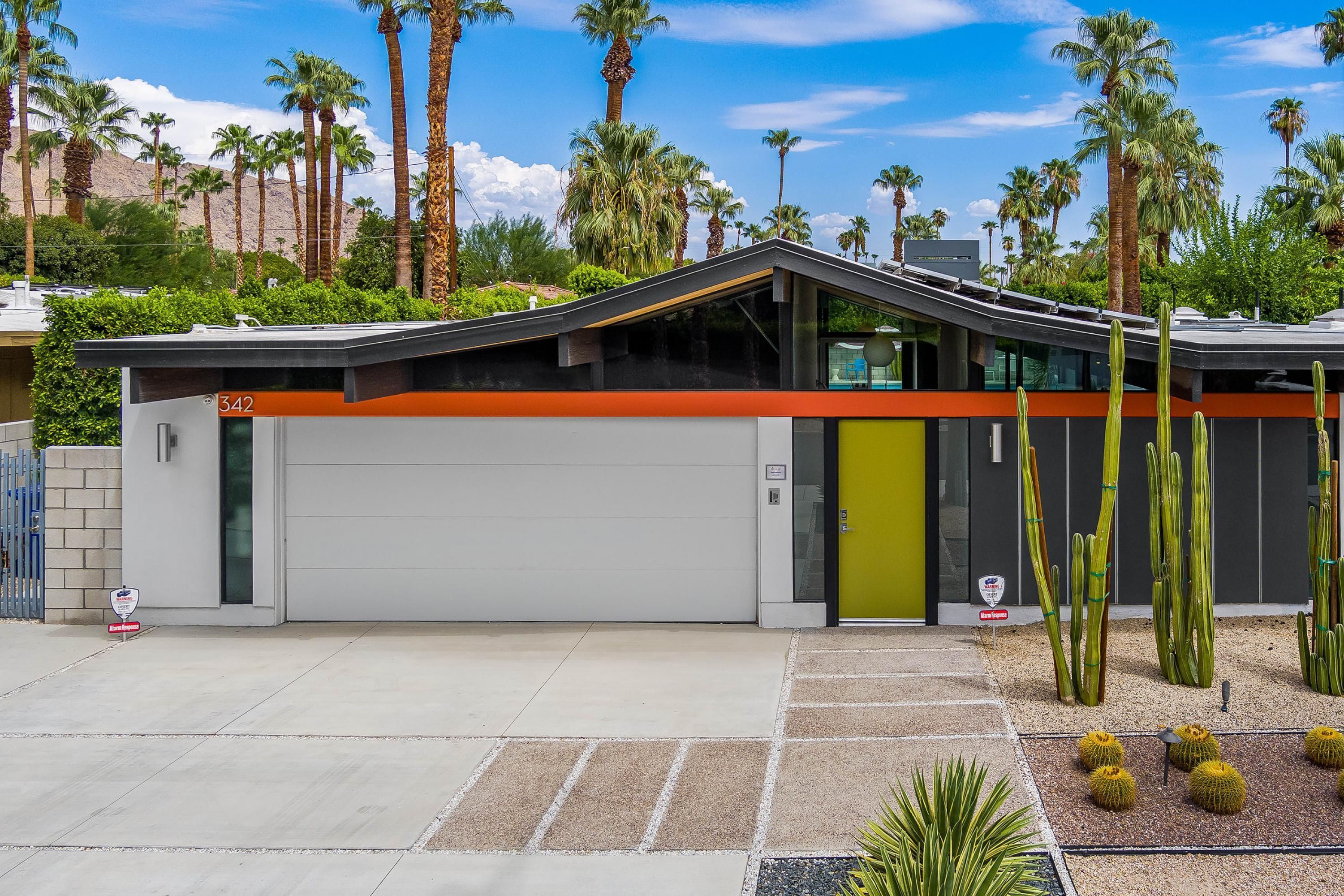 A modern building with a garage, a green door, and a parking area with cacti and succulents.