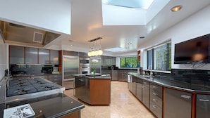 Una cocina moderna con una isla central, electrodomésticos de acero inoxidable y un amplio ventanal que proporciona luz natural.