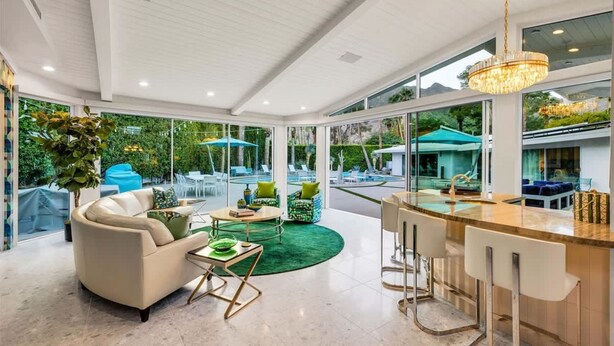 Amplio espacio interior con barra, asientos y ventanas grandes con vista a una piscina.