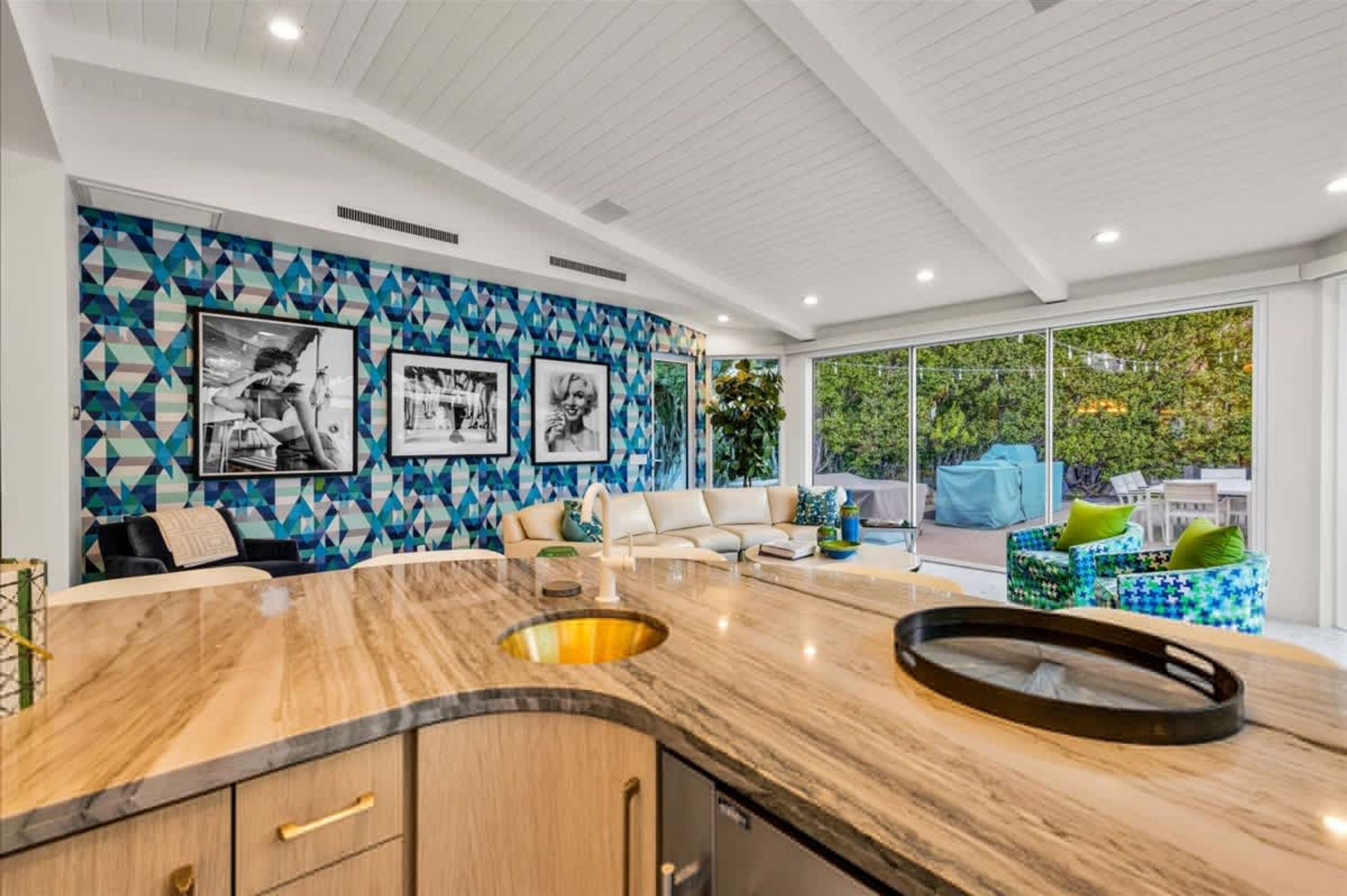 A modern kitchen with a marble countertop, a built-in sink, and a large window overlooking a lush garden.