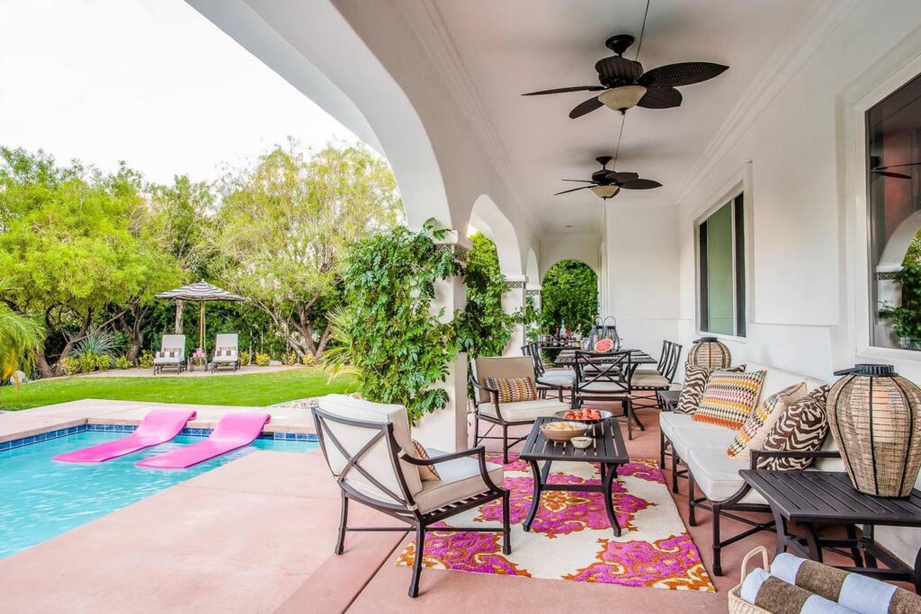 A covered outdoor area with a pool, lounge chairs, and a seating area with tables and chairs.