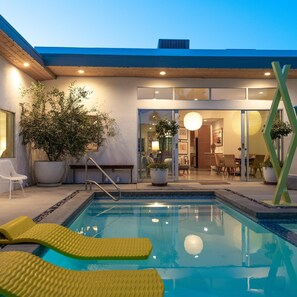 Un área de piscina moderna con vista despejada, sillas de descanso y una planta en maceta.
