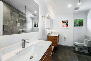 Un baño moderno con un espejo grande, un tocador doble, inodoro y zona de ducha.
