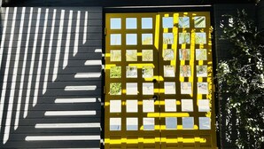 Ein modernes Gebäude mit einer auffälligen schwarz-weißen Streifenfassade, einer großen gelben Tür mit mehreren Fenstern und einem Deckenventilator.