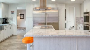 Eine moderne Küche mit einer zentralen Kochinsel, Edelstahlgeräten und Pendelleuchten.