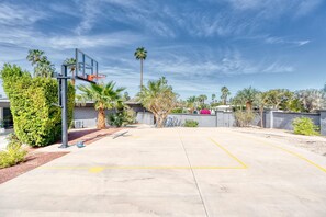An outdoor basketball court with a hoop, surrounded by palm trees and shrubs. - The Yellow Door on Shadow Mountain (Palm Desert)