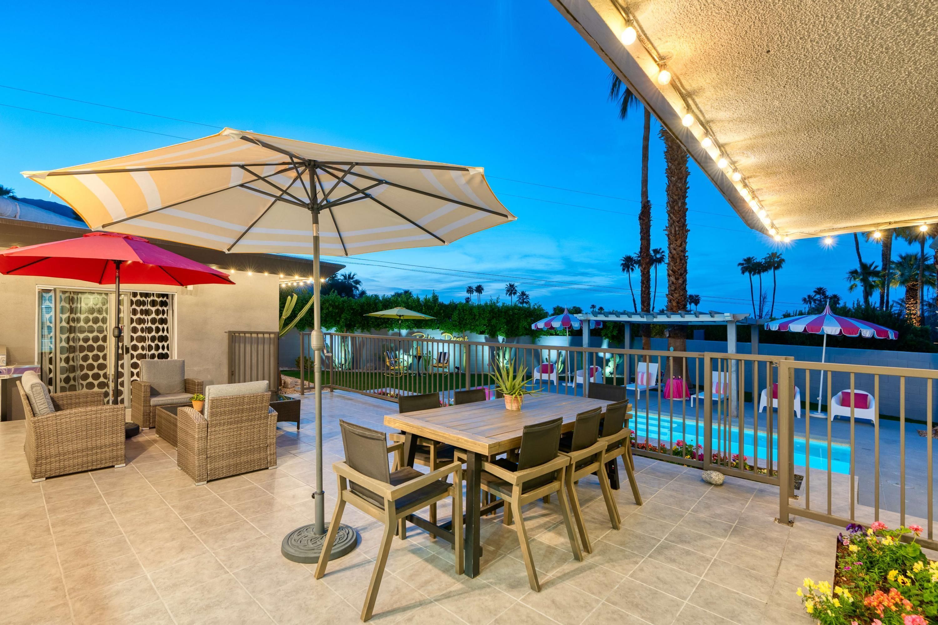 An outdoor patio with a pool, wicker furniture, and umbrellas.