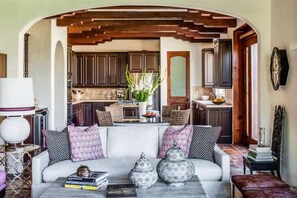 Un salon chaleureux avec un canapé blanc, des coussins décoratifs et une table basse ornée de livres et de vases.