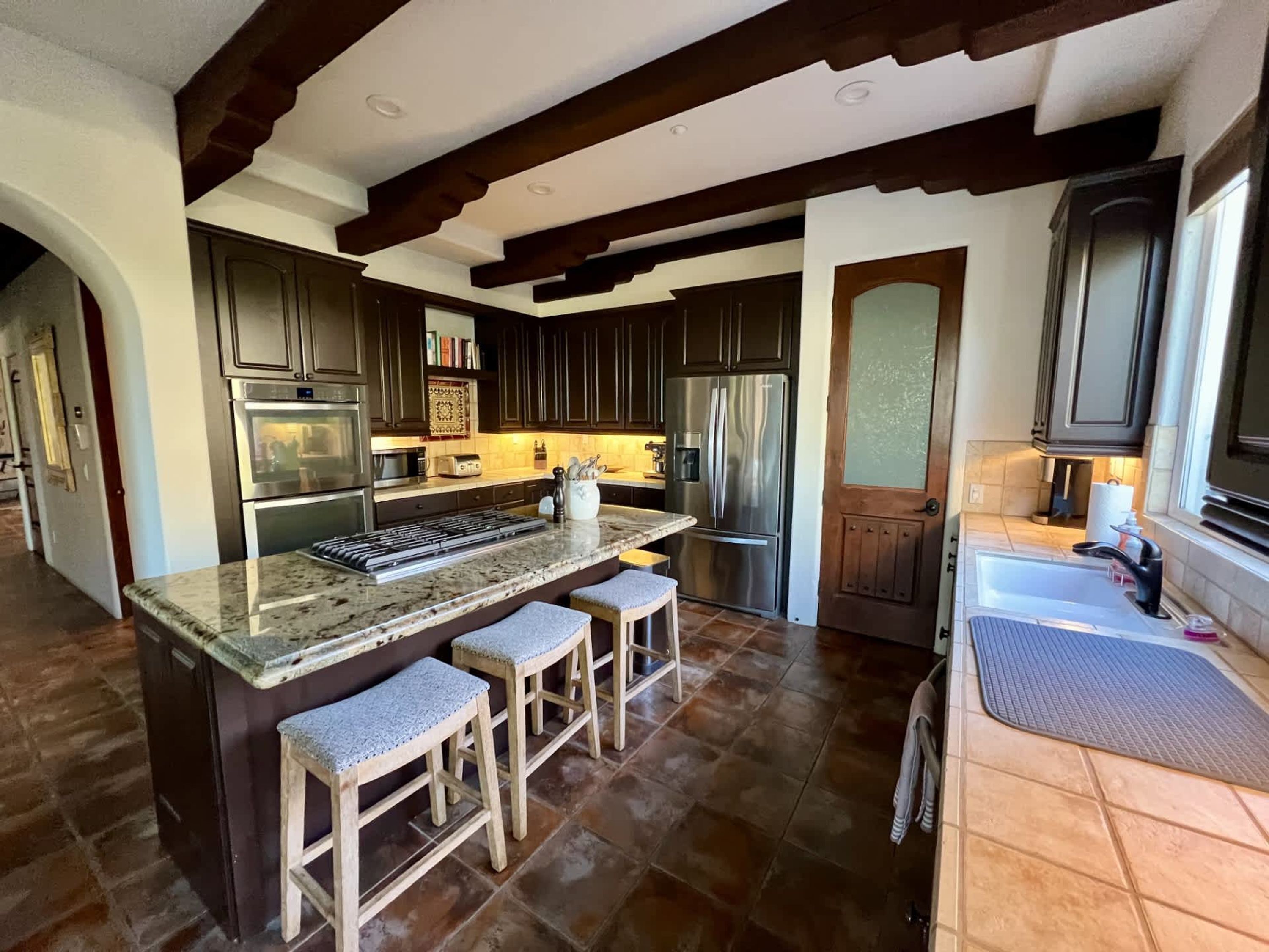 A modern kitchen with dark wood cabinets, stainless steel appliances, and a granite countertop.