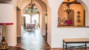 A hallway with arches, a chandelier, and a dining area in the background. - Villa Vista - Spanish Luxury Pool Wifi (Palm Springs)