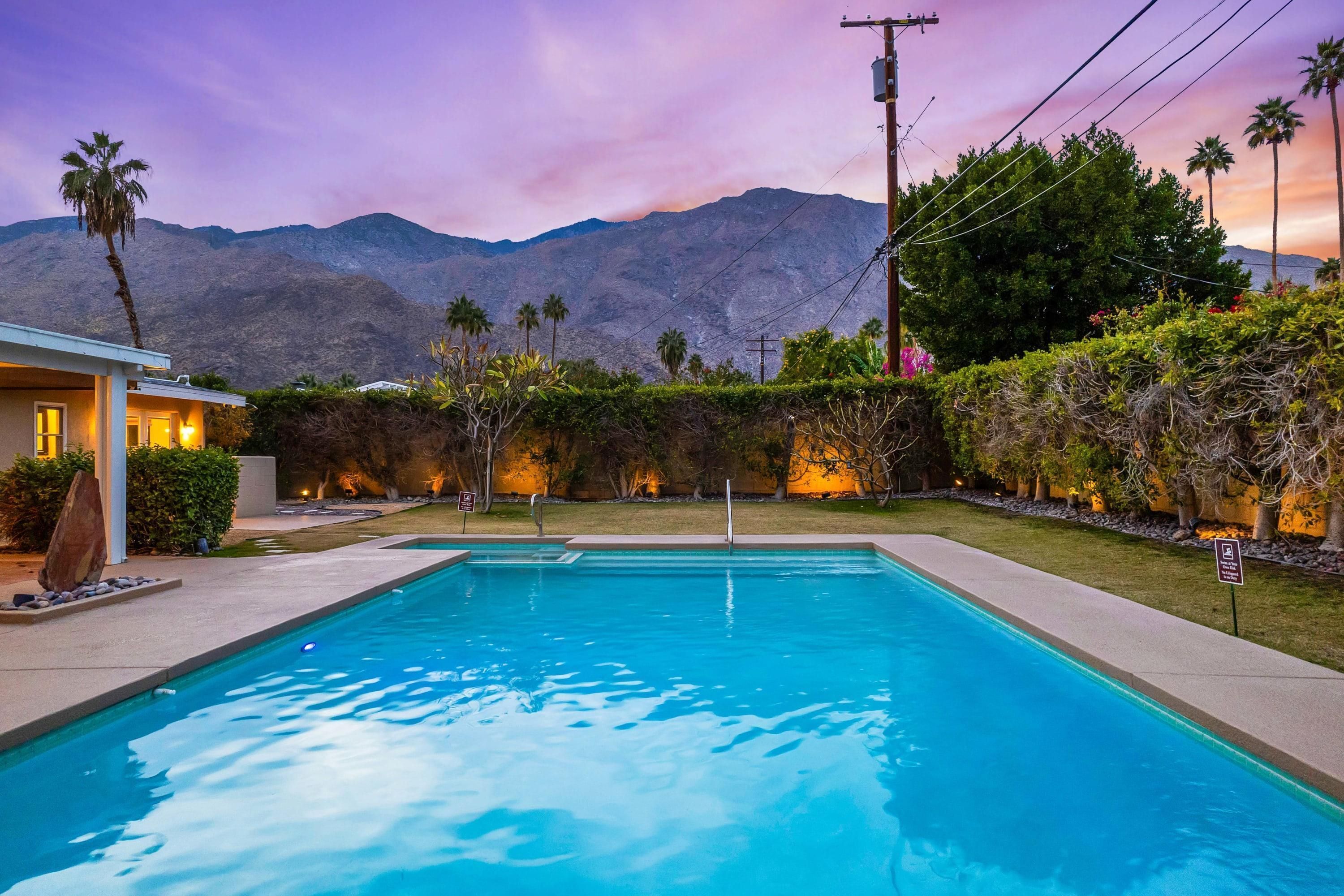Una piscina con vistas a montañas y un patio bien iluminado.