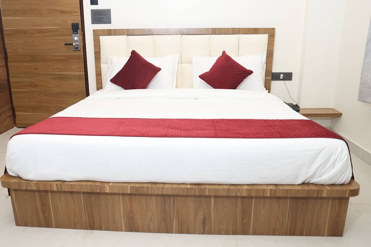 A large bed with a wooden frame, white bedding, and red pillows.