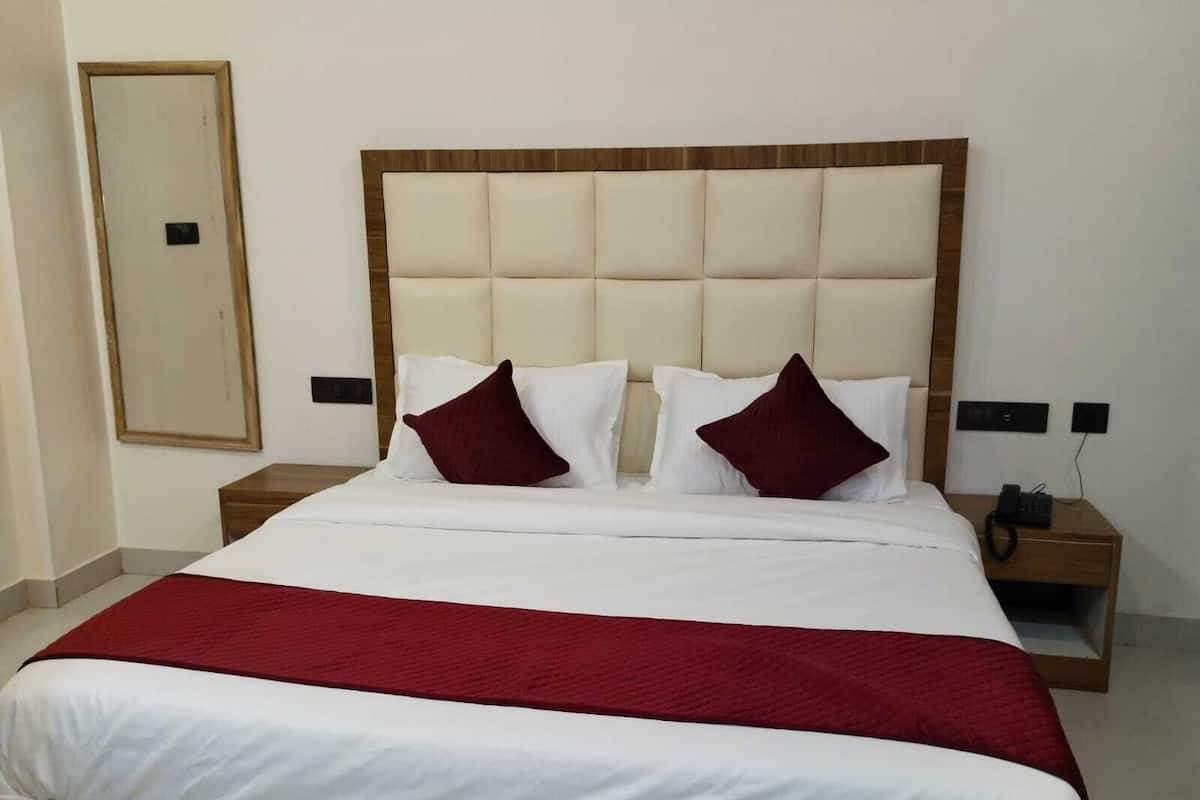 A hotel room with a large bed, two bedside tables, a mirror, and a red throw blanket.