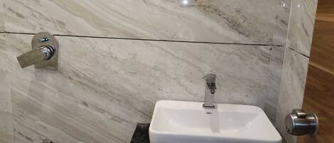 A bathroom with a white sink on a black countertop, a silver faucet, and a door with a silver handle.