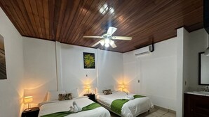 A hotel room with two beds, wooden ceiling, a ceiling fan, a painting, and a bathroom with a mirror. - The Palms At Coco Beach (Carrillos)