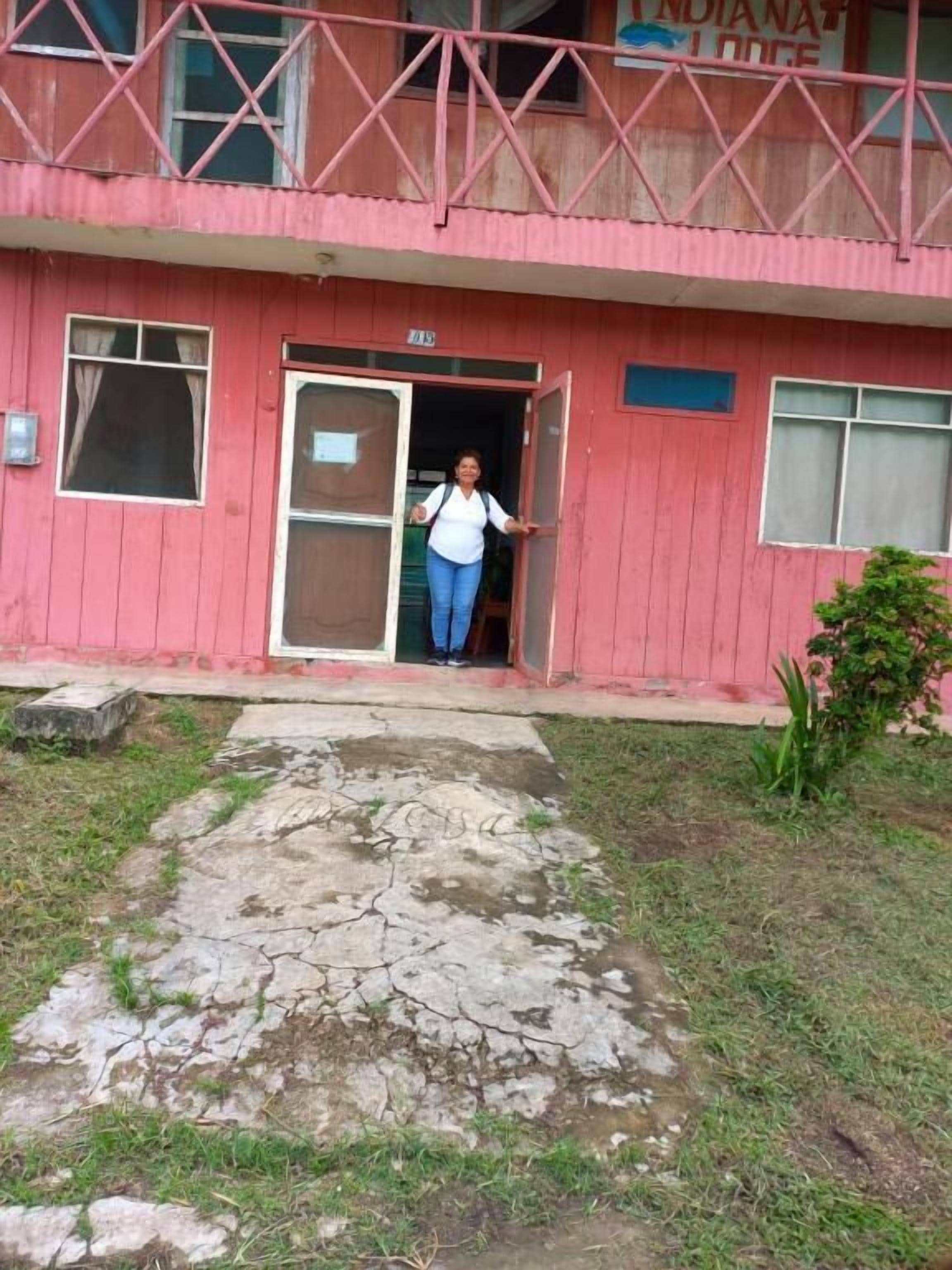 Un edificio rojo con balcón, puerta y un pequeño letrero.