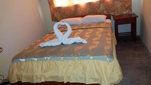 A neatly made bed with a decorative swan towel arrangement, a patterned headboard, and a small bedside table. - Indiana Lodge (Indiana)