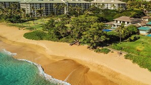 A resort with multiple buildings, a beach, and clear blue waters.