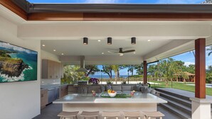 Een moderne keuken met een groot eiland, barstoelen en uitzicht op de oceaan.