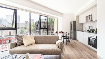 Un apartamento moderno con un ventanal grande, un sofá, una mesa de comedor y una zona de cocina.
