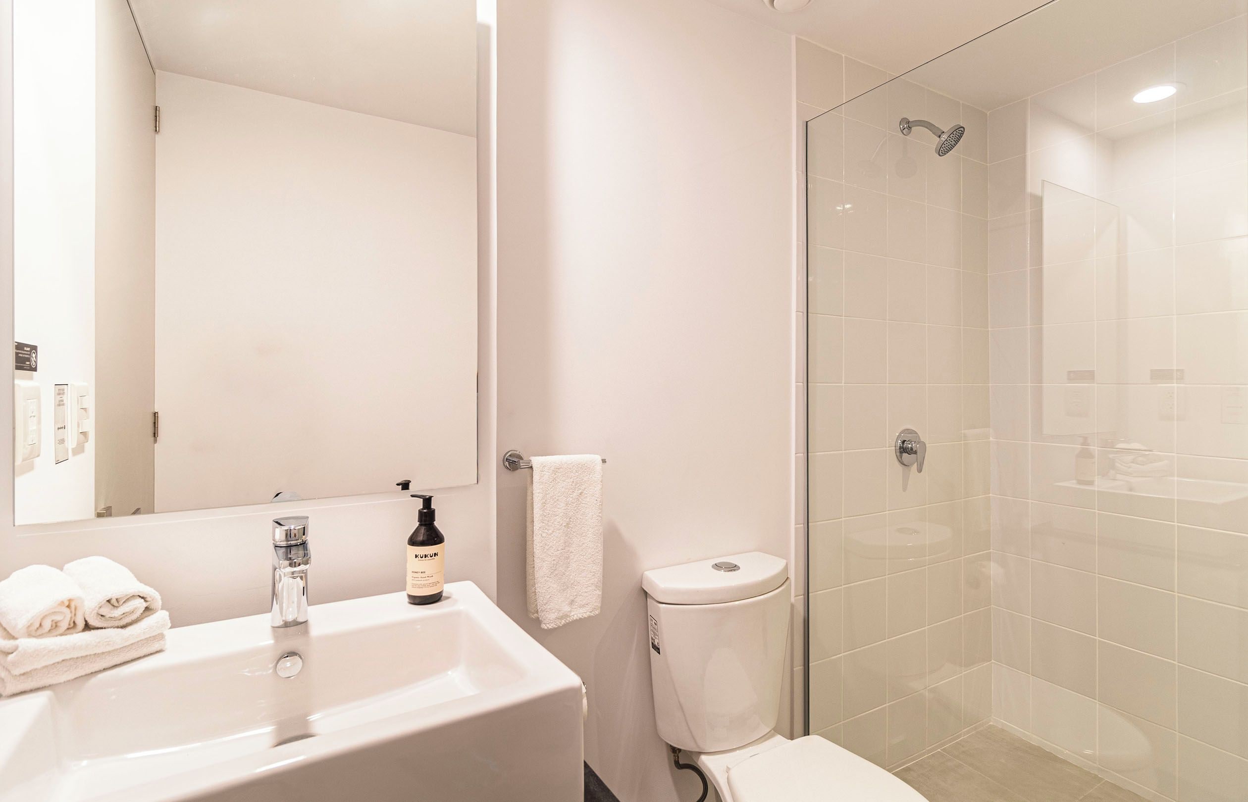 Een moderne badkamer met een wastafel, spiegel, toilet en douche.