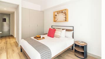 Un dormitorio moderno con cama, mesita de noche y una obra de arte colgada en la pared.