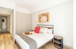 Un dormitorio moderno con cama, mesita de noche y una obra de arte colgada en la pared.