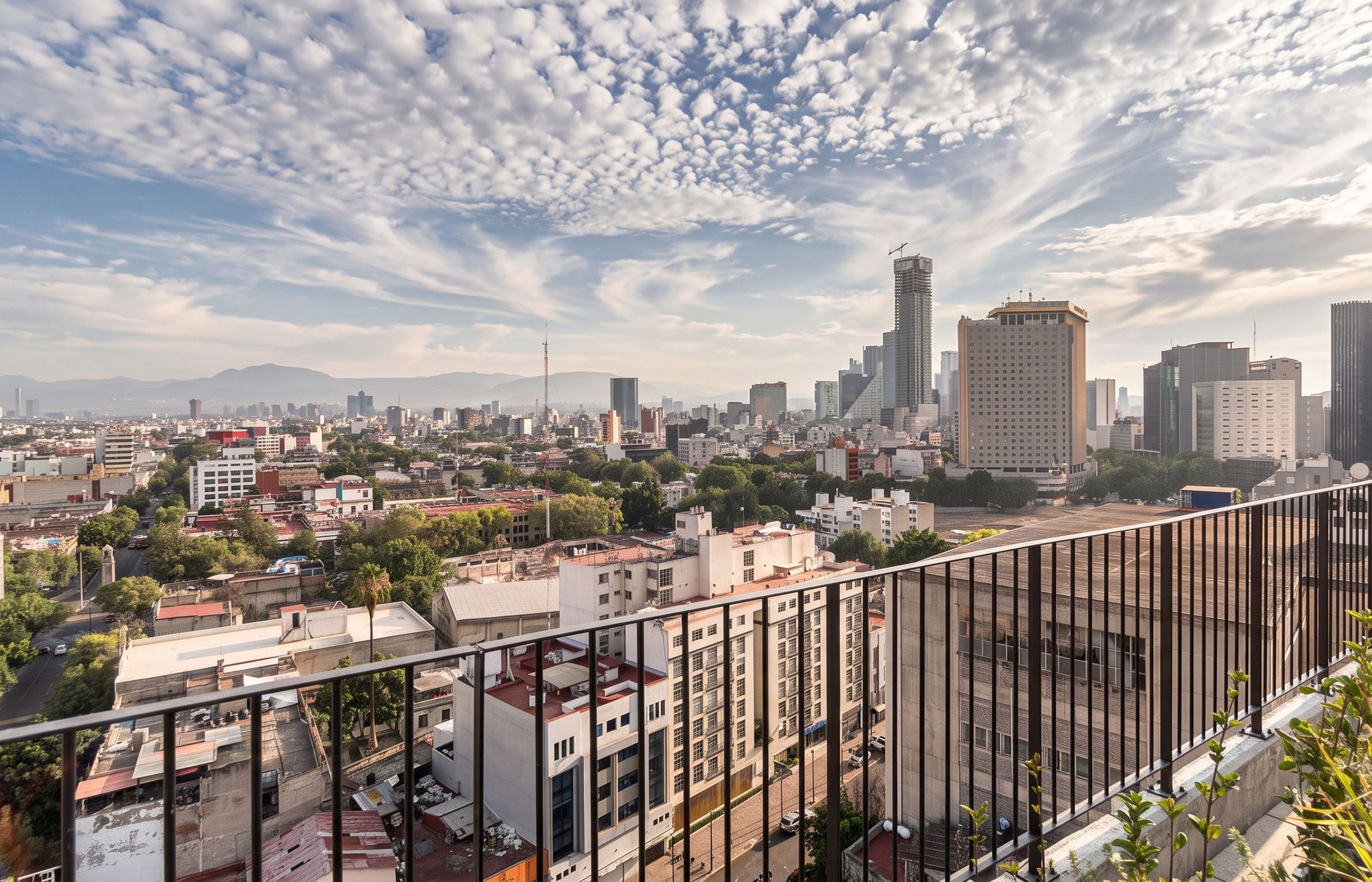 Une vue urbaine présentant une variété de hauteurs de bâtiments, dont un gratte-ciel imposant, sous un ciel partiellement nuageux.