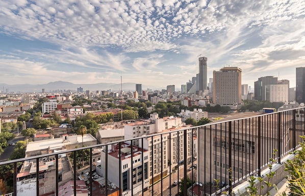 Un paisaje urbano con edificios de diferentes alturas, incluyendo un rascacielos destacado, bajo un cielo parcialmente nublado.