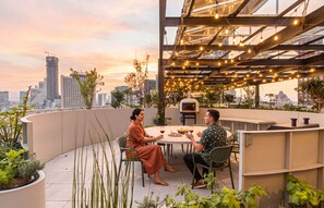 A rooftop dining area with a city view, outdoor seating, and string lights. - Kukun Reforma Downtown (Mexico City)