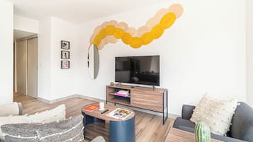 A modern living room with a flat-screen TV, a coffee table, and a sofa.