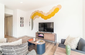 Una sala moderna con un televisor de pantalla plana, una mesa de centro y un sofá.