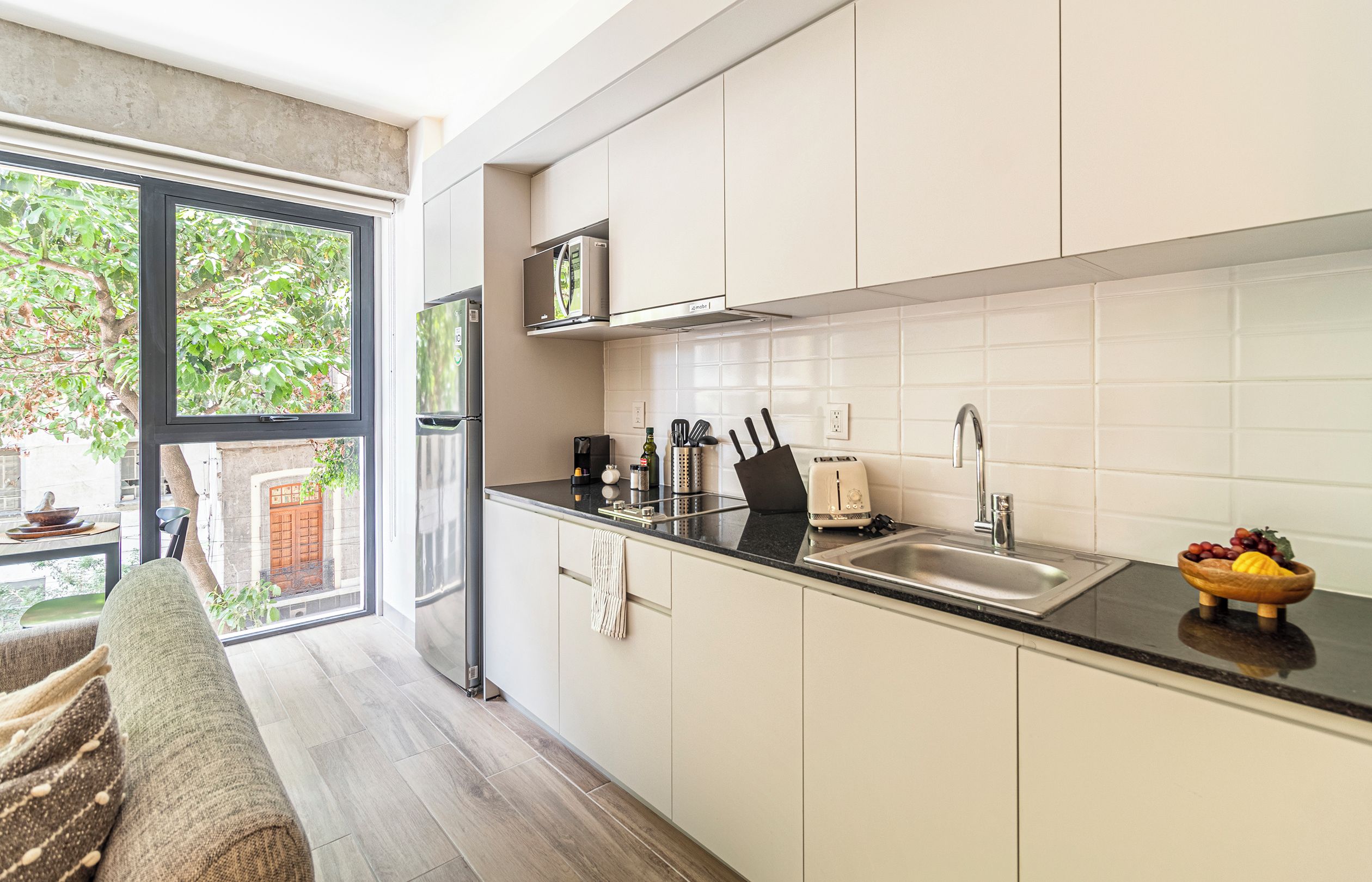 A modern kitchen with a large window, stainless steel appliances, and a black countertop.