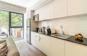 A modern kitchen with a large window, stainless steel appliances, and a black countertop. - Kukun Reforma Downtown (Mexico City)
