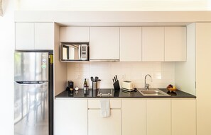 A modern kitchen with a stainless steel refrigerator, a microwave, and a toaster on the countertop. - Kukun Reforma Downtown (Mexico City)