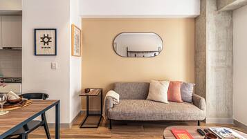 Una sala de estar moderna con un sofá, una mesa de centro, una mesita auxiliar y un cuadro enmarcado en la pared.