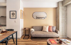 Una sala de estar moderna con un sofá, una mesa de centro, una mesita auxiliar y un cuadro enmarcado en la pared.