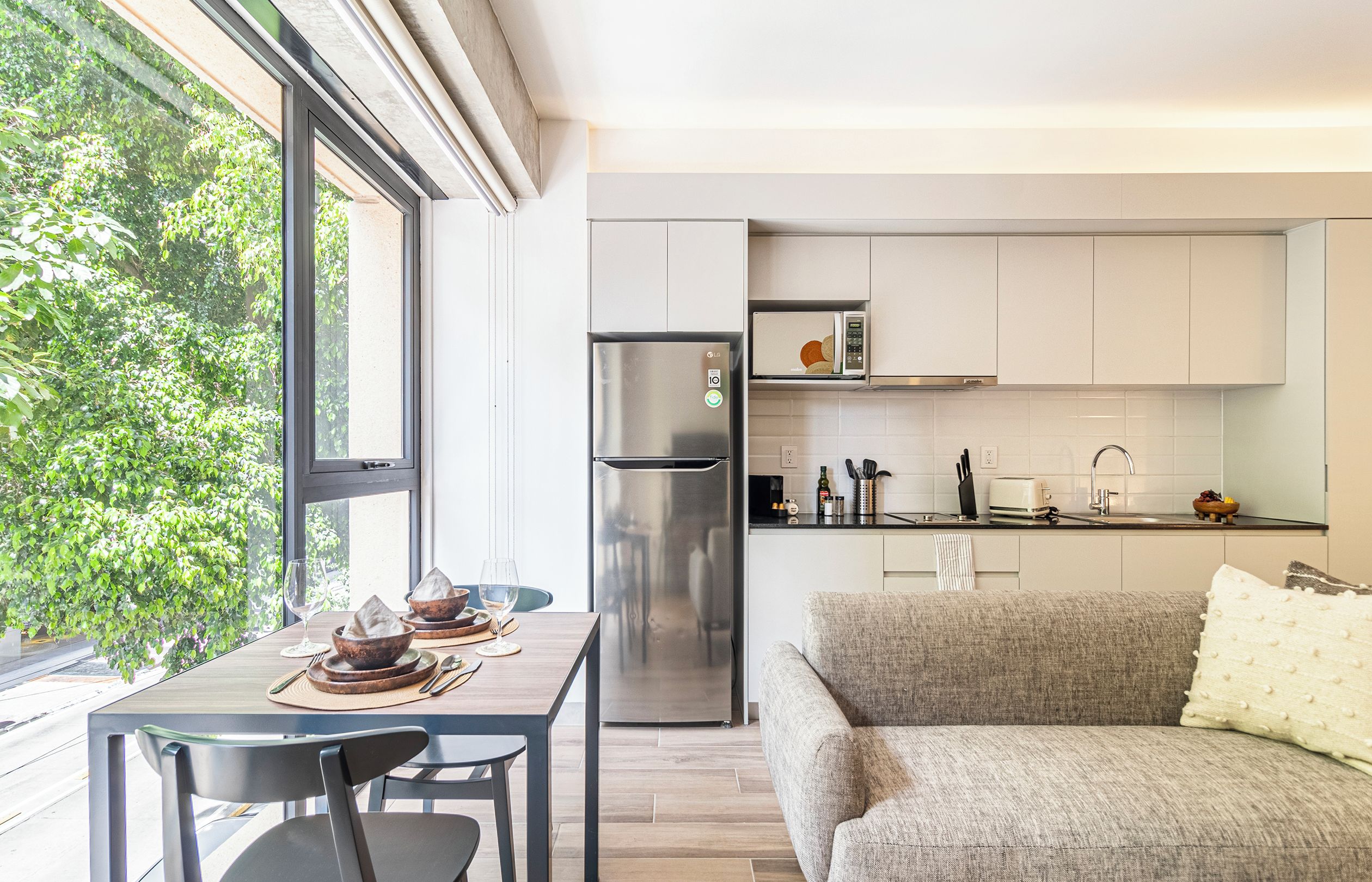 Una cocina moderna con refrigerador, microondas y gabinetes blancos.