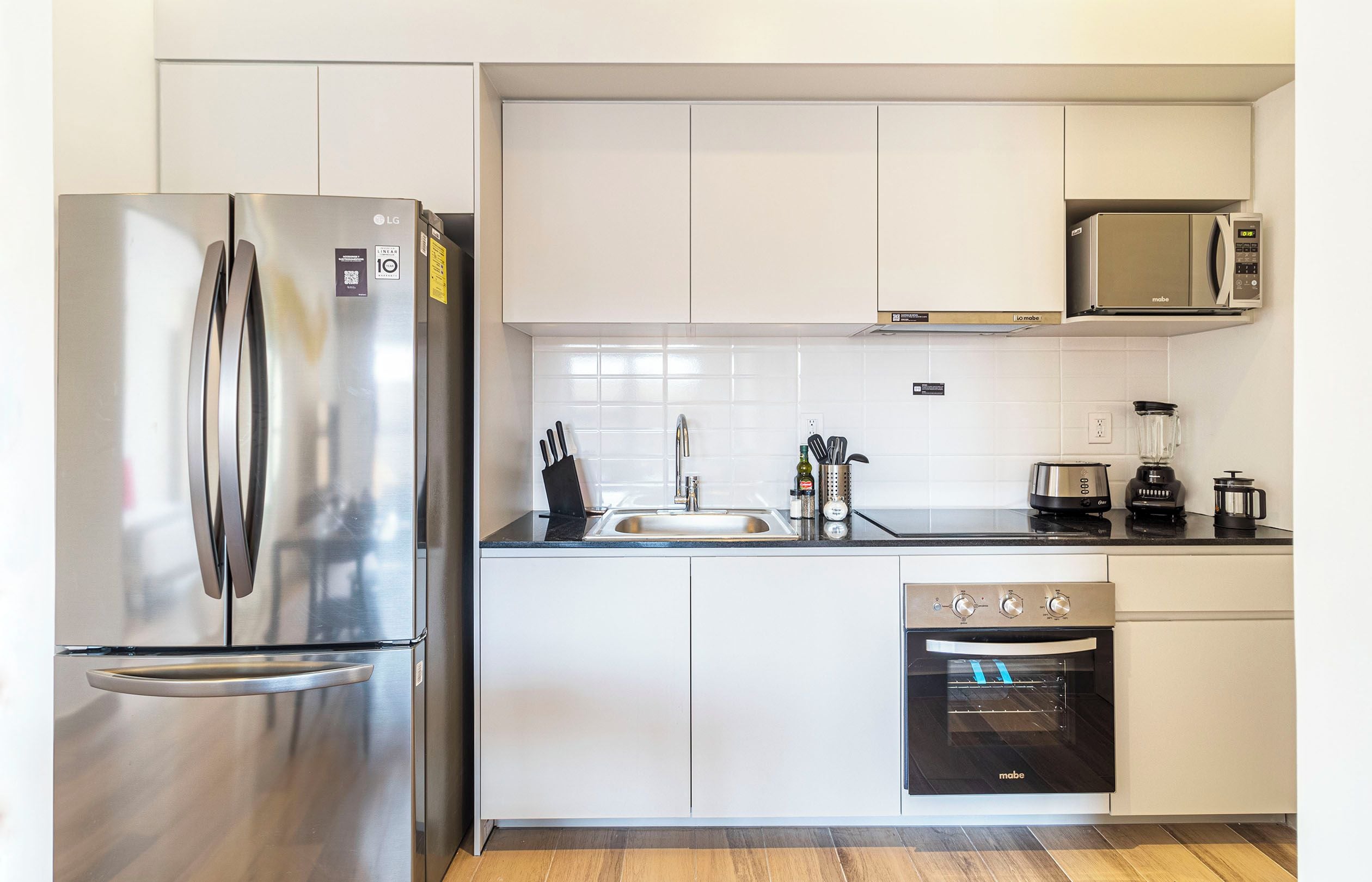 A modern kitchen with a stainless steel refrigerator, a microwave, a sink, and a built-in oven.
