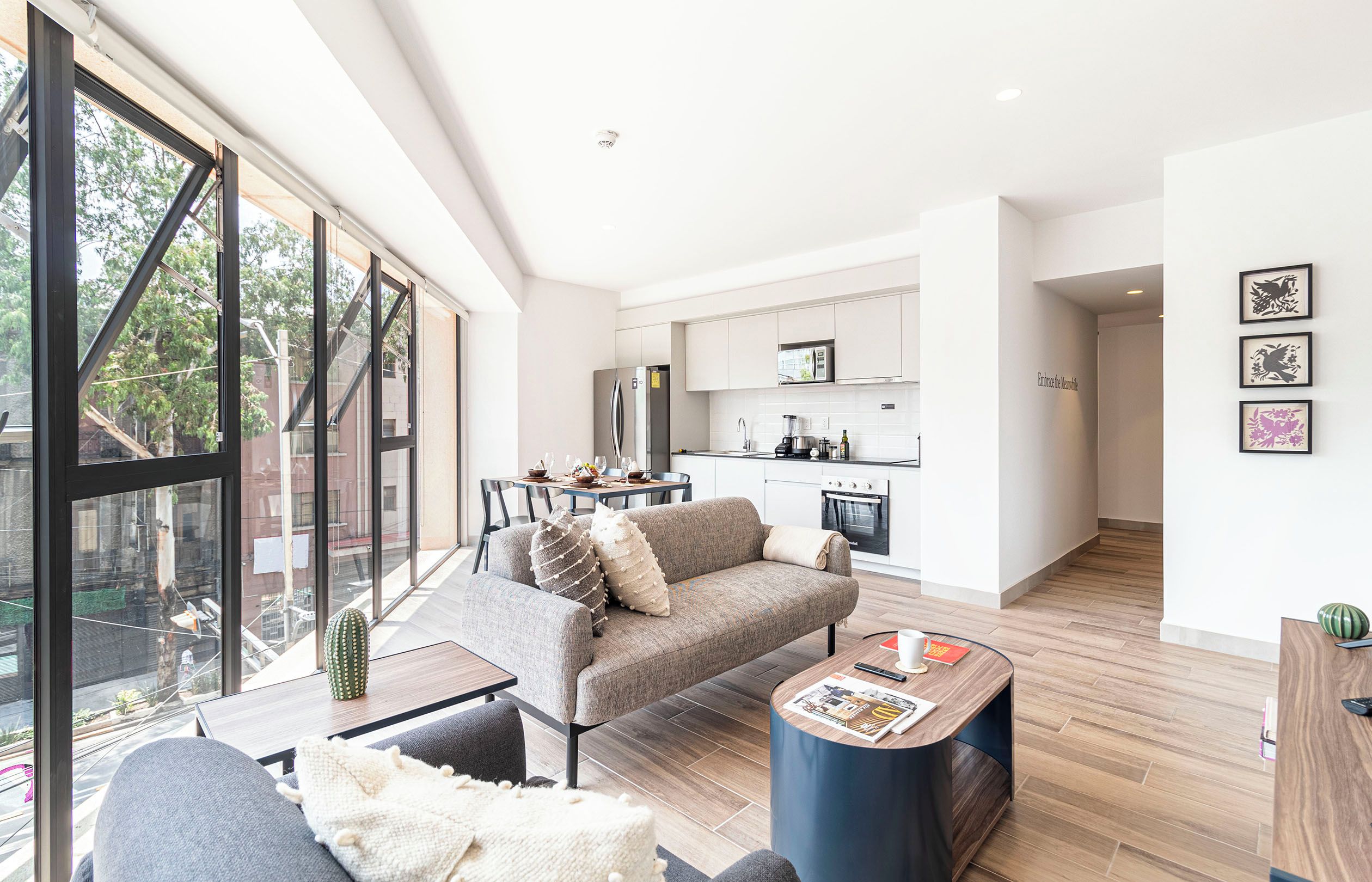 A modern living room with a sofa, coffee table, and a view through large windows.