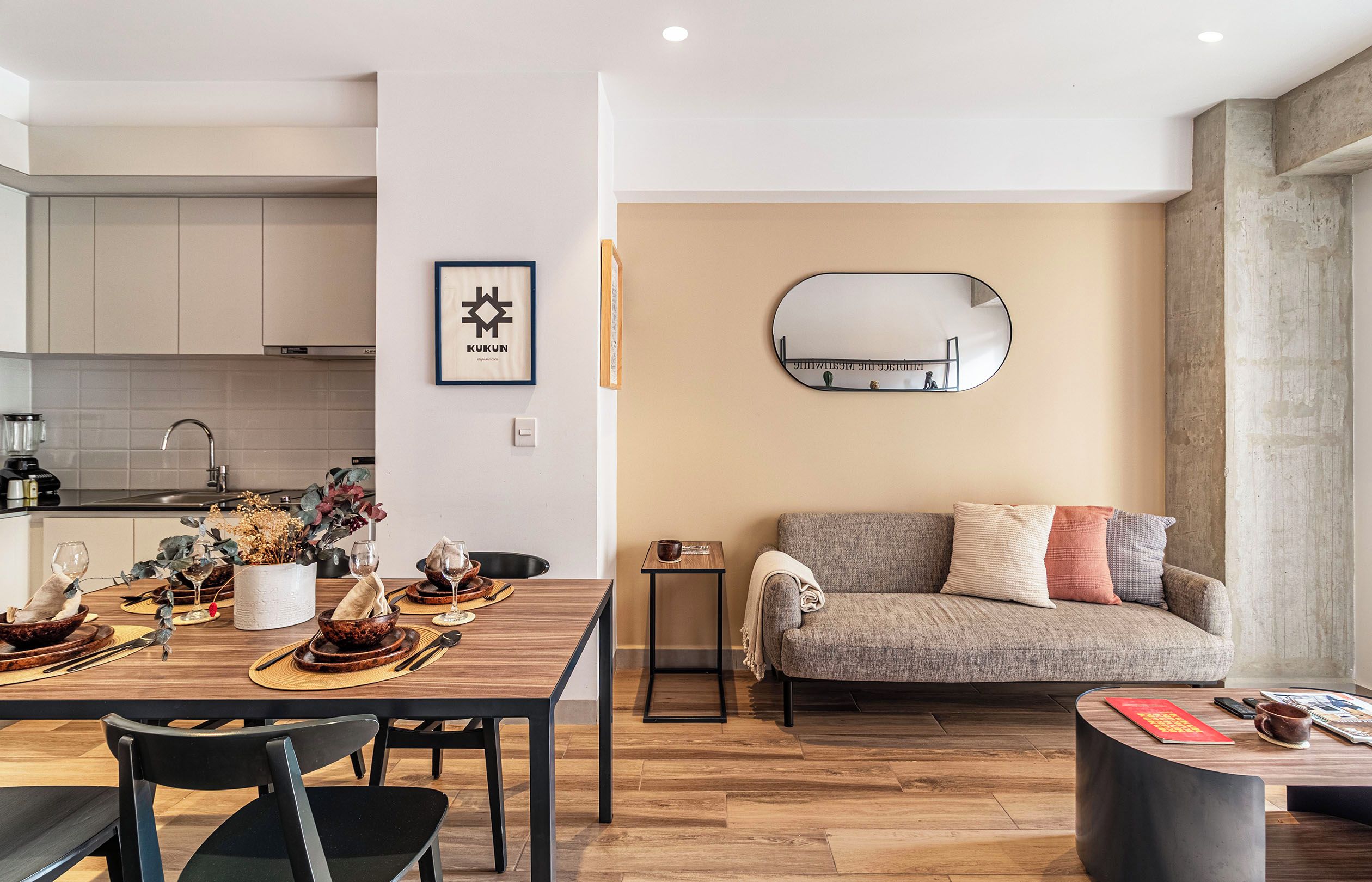 Un espacio habitable moderno con comedor, sofá y un espejo redondo en la pared.