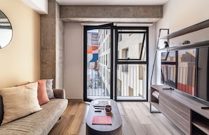 A modern living room with a sofa, coffee table, and a TV on a wooden stand. - Kukun Reforma Downtown (Mexico City)