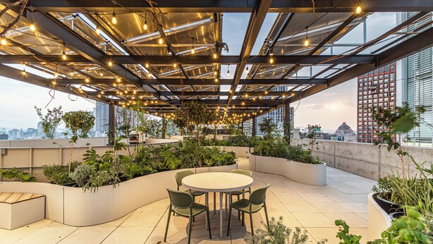 A rooftop terrace with a round table and chairs, surrounded by planters with greenery, and a cityscape view. - Kukun Reforma Downtown (Mexico City)