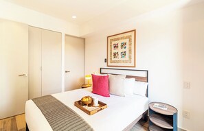 A hotel room with a bed, a bedside table with a lamp, a small round table, and a wall-mounted artwork. - Kukun Reforma Downtown (Mexico City)