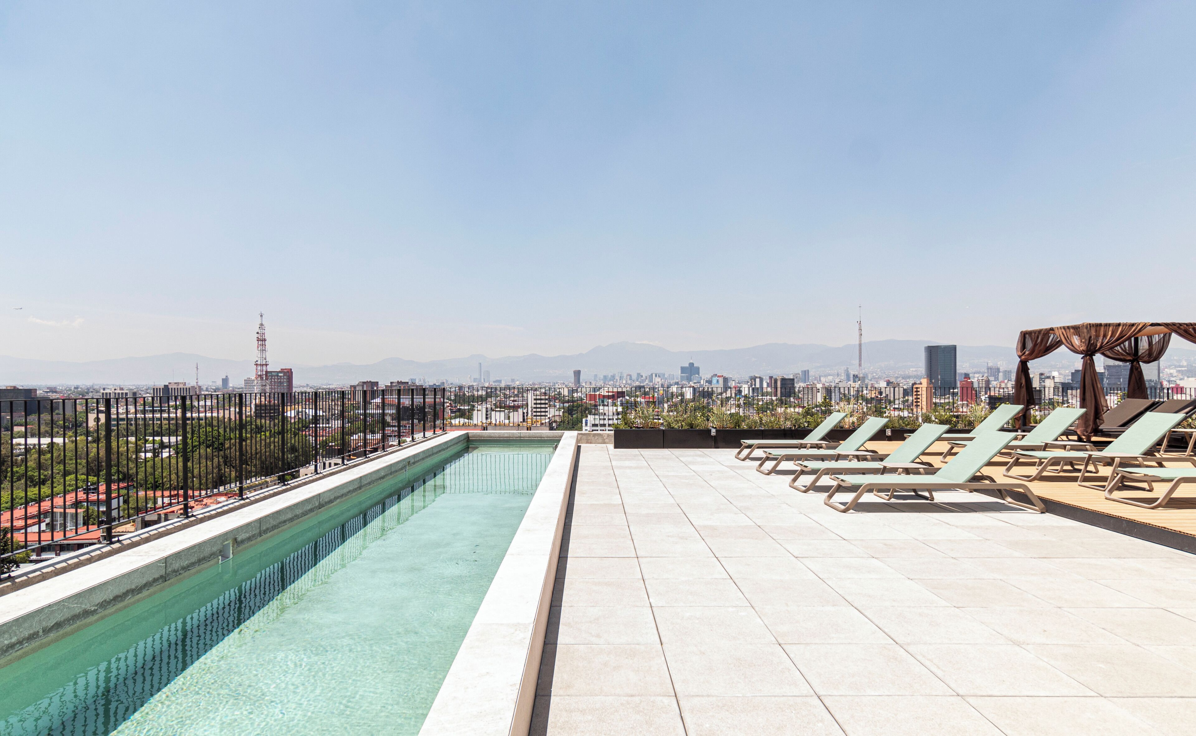Una piscina al aire libre, sombrillas, sillones reclinables de piscina