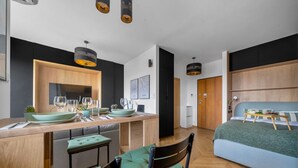 A modern kitchen with a dining area, a bed with a side table, and a small bathroom. - Warsaw Wola Studio - Balcony & Workspace -by Rentujemy (Warszawa)
