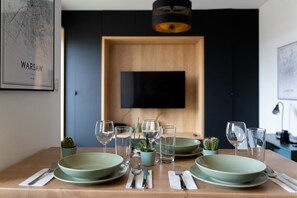 A dining table set with plates, glasses, and cutlery, with a small cactus plant on the table.